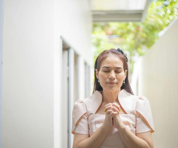 Person meditating calmly outdoors with a serene natural background.